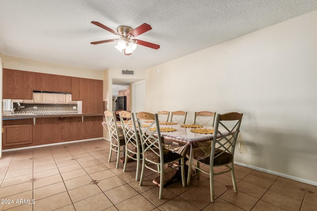 dining space featuring a textured ceiling, ceiling fan, light tile patterned floors, and sink