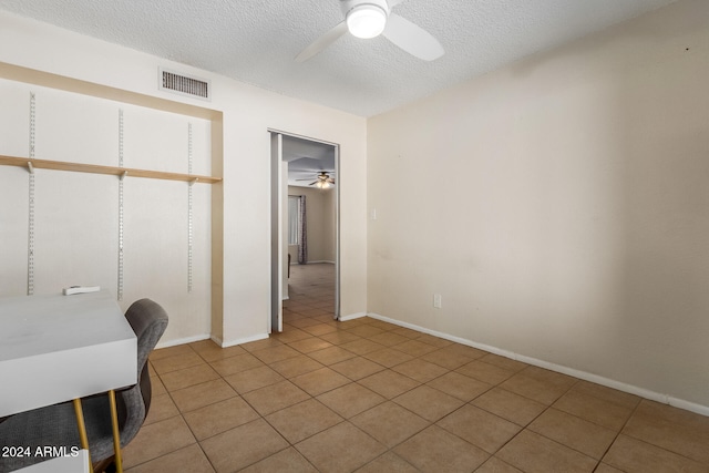 tiled office space with a textured ceiling and ceiling fan