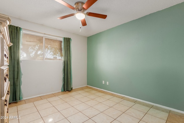 empty room featuring light tile patterned floors, a textured ceiling, and ceiling fan