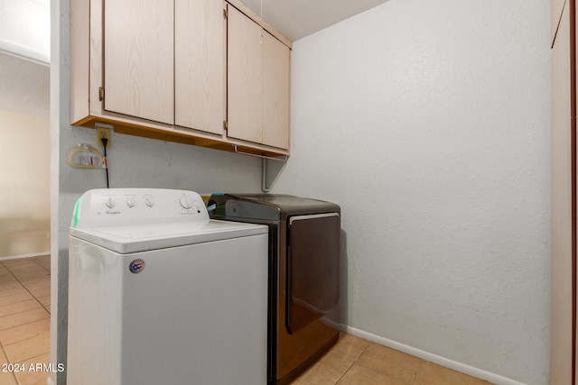 laundry area featuring separate washer and dryer, light tile patterned floors, and cabinets