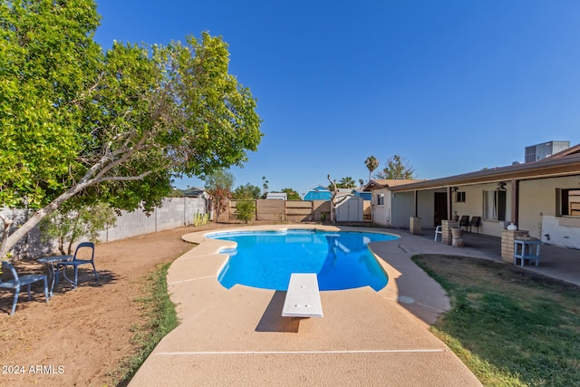 view of swimming pool with a patio, a diving board, and a storage shed