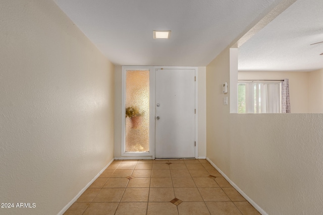 entryway featuring light tile patterned floors, a wealth of natural light, and ceiling fan