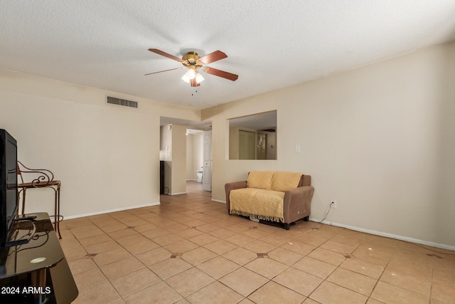 living area featuring ceiling fan, light tile patterned floors, and a textured ceiling