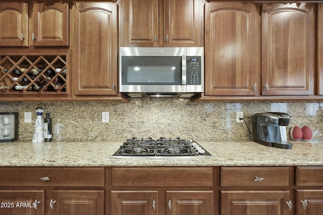 kitchen featuring stainless steel appliances, tasteful backsplash, and light stone countertops