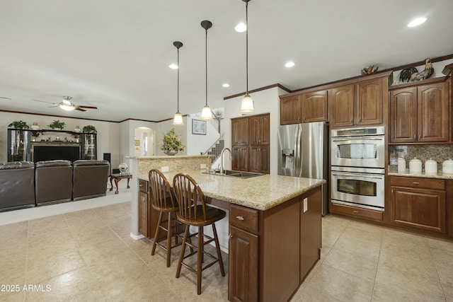 kitchen featuring a breakfast bar, sink, a center island with sink, appliances with stainless steel finishes, and pendant lighting