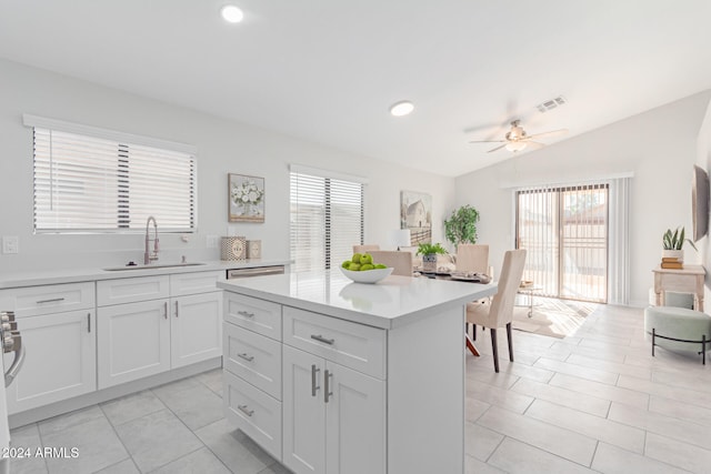 kitchen featuring white cabinetry, ceiling fan, sink, vaulted ceiling, and a kitchen island