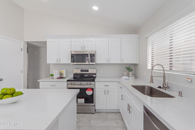 kitchen with sink, white cabinets, stainless steel appliances, and vaulted ceiling