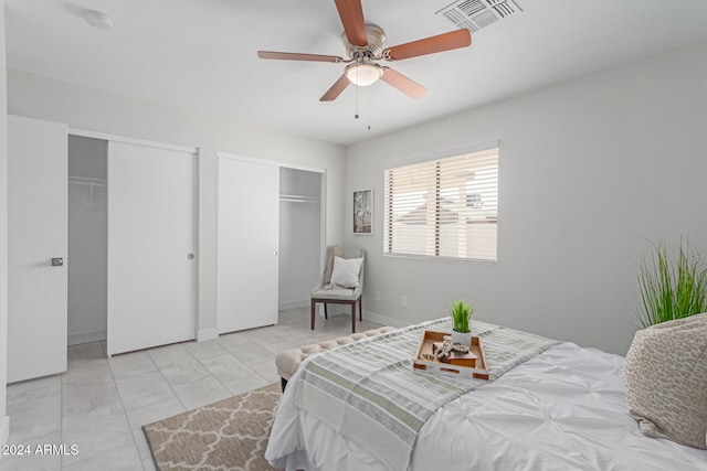 tiled bedroom featuring two closets and ceiling fan