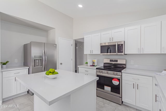 kitchen featuring white cabinets, a center island, stainless steel appliances, and vaulted ceiling