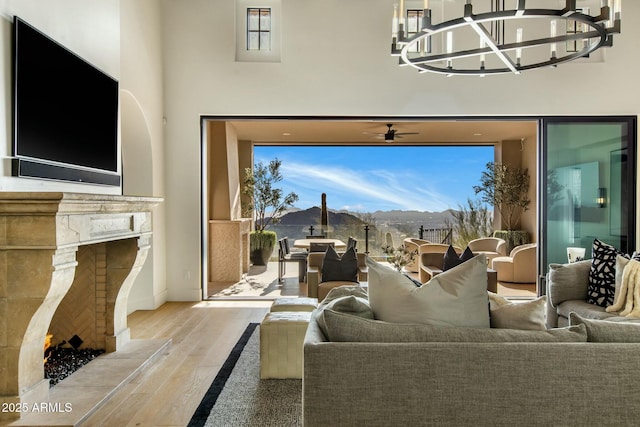 living area featuring light wood-style floors, a notable chandelier, and a tiled fireplace