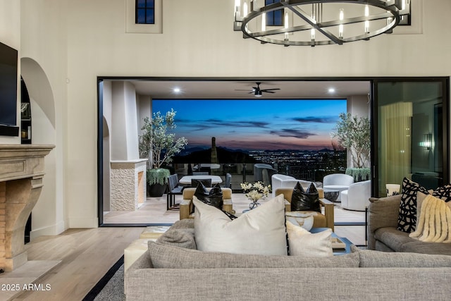 living area featuring light wood-style floors, baseboards, a towering ceiling, and a fireplace with flush hearth