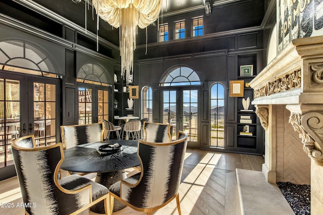 dining space with ornamental molding, french doors, a decorative wall, and a high ceiling
