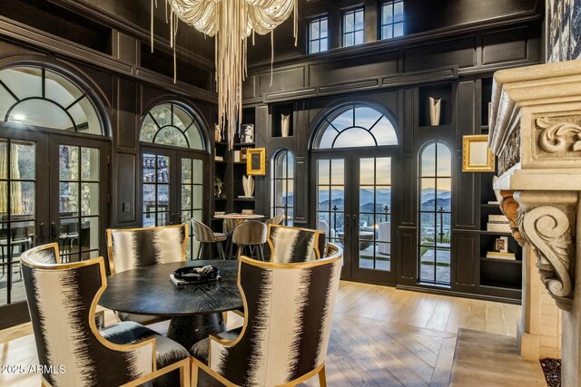 dining space featuring french doors, a decorative wall, and a towering ceiling