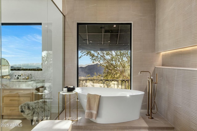 bathroom with a freestanding tub, a mountain view, and tile walls