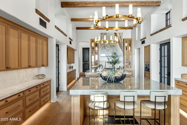 kitchen featuring light wood-style flooring, a notable chandelier, a kitchen island, a kitchen breakfast bar, and hanging light fixtures