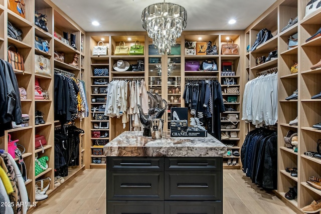 walk in closet with light wood-style flooring and a notable chandelier