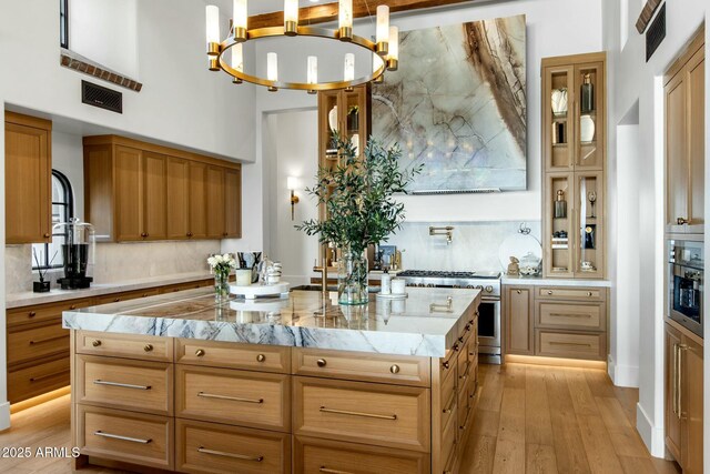 kitchen featuring light countertops, high end stainless steel range oven, visible vents, glass insert cabinets, and a kitchen island