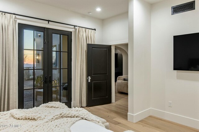 bedroom with light wood finished floors, baseboards, visible vents, arched walkways, and recessed lighting