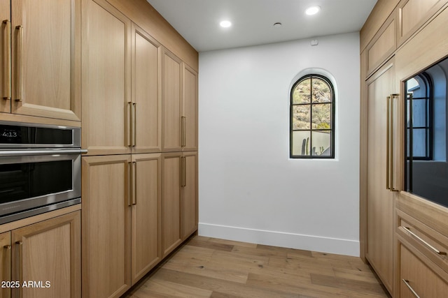 kitchen with recessed lighting, stainless steel oven, baseboards, light brown cabinetry, and light wood finished floors