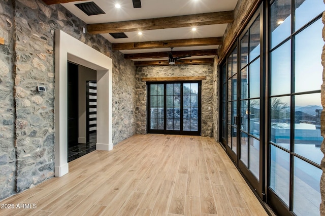 empty room with light wood-style floors, visible vents, beamed ceiling, and ceiling fan