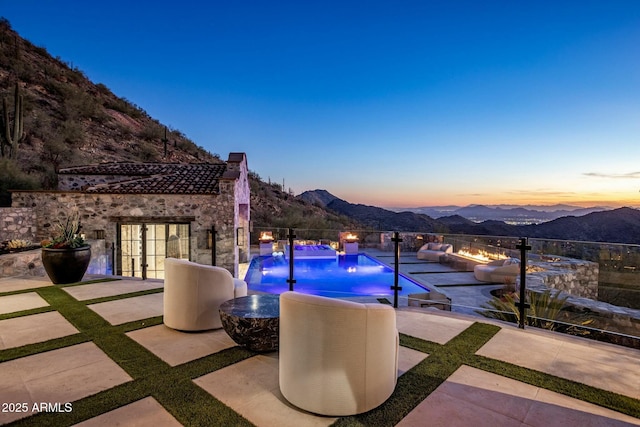 pool at dusk with a patio, a mountain view, and a fenced in pool