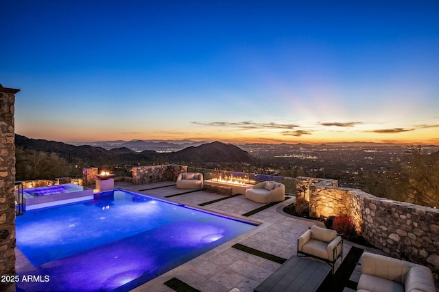 view of pool featuring an outdoor living space with a fire pit, a mountain view, a hot tub, and a patio