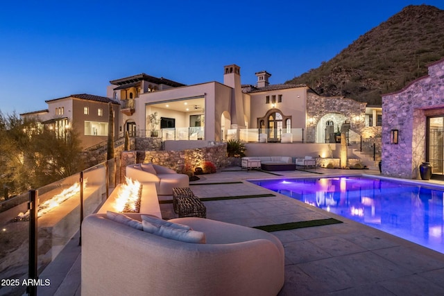 pool at dusk with a patio and an outdoor pool