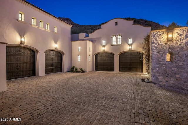 mediterranean / spanish house with a garage, decorative driveway, and stucco siding