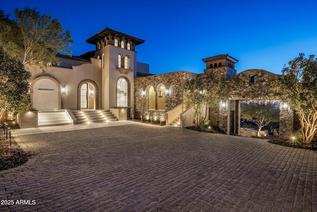 view of front facade with stairs, decorative driveway, and stucco siding