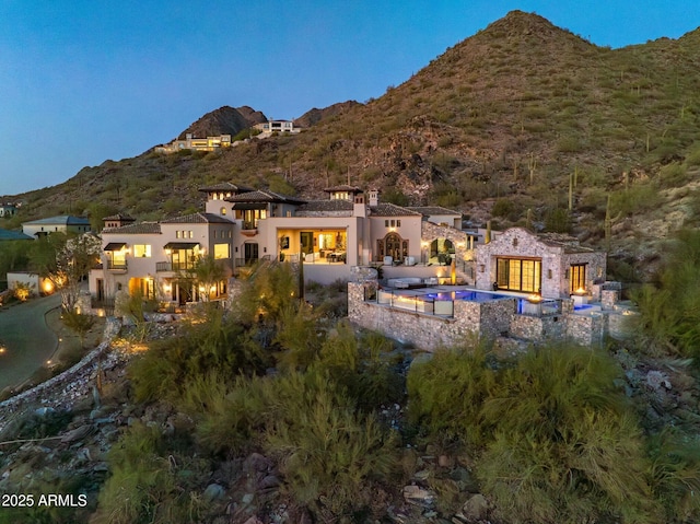 rear view of house featuring stone siding, a mountain view, and stucco siding