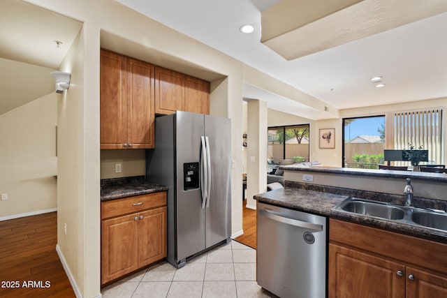 kitchen with a sink, dark countertops, recessed lighting, appliances with stainless steel finishes, and brown cabinetry