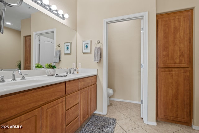 bathroom with tile patterned flooring, double vanity, toilet, and a sink