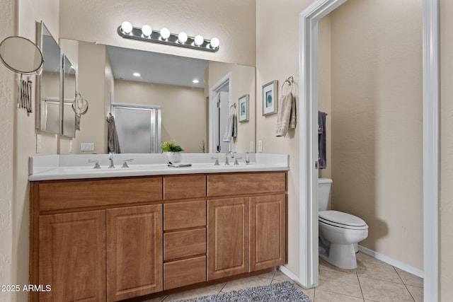 bathroom featuring double vanity, a sink, tile patterned flooring, a shower stall, and toilet