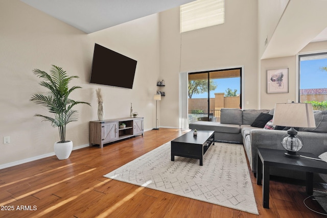 living area with baseboards, a high ceiling, and wood finished floors