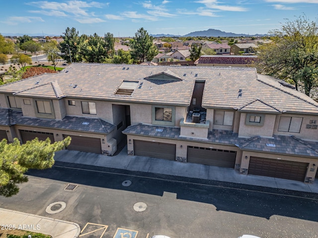 multi unit property with an attached garage, a mountain view, a residential view, and stucco siding