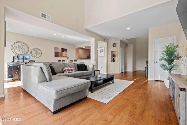 living room with recessed lighting, visible vents, baseboards, and light wood finished floors