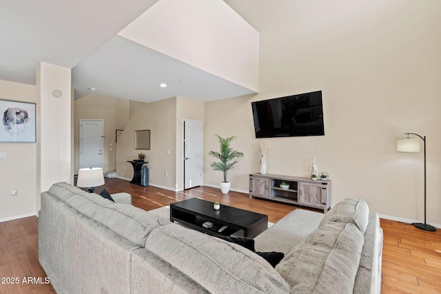 living area featuring baseboards, wood finished floors, and vaulted ceiling