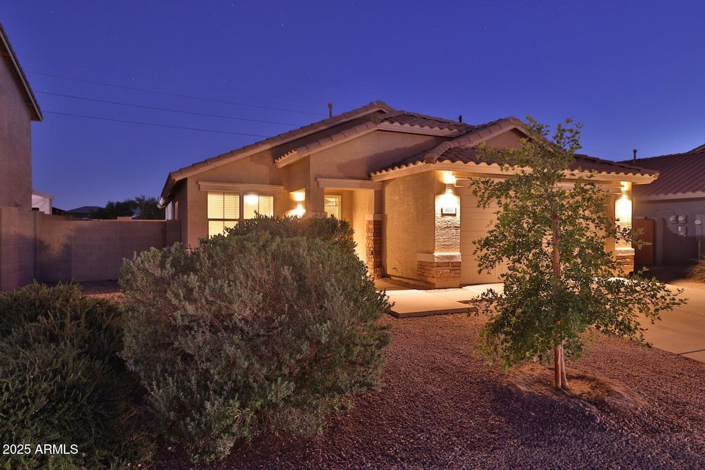view of front of home with stucco siding, fence, a tiled roof, and a garage