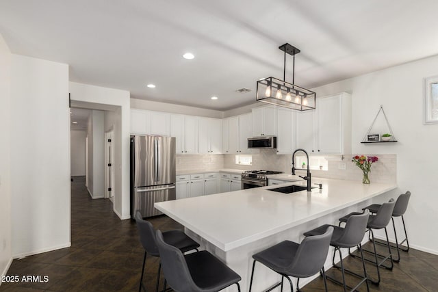 kitchen featuring a breakfast bar area, appliances with stainless steel finishes, a sink, and tasteful backsplash
