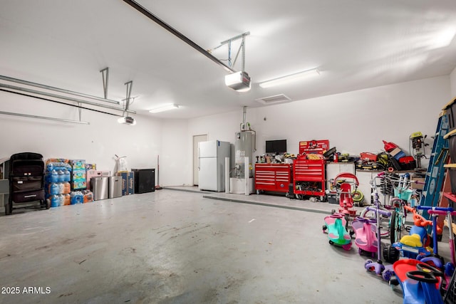 garage with freestanding refrigerator, a workshop area, a garage door opener, and water heater