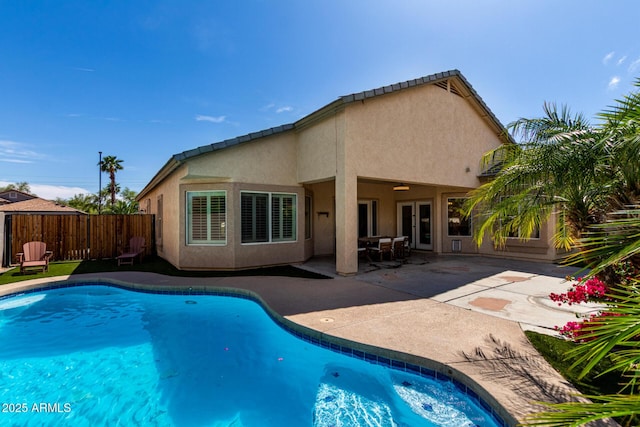 back of house featuring fence, a fenced in pool, a patio area, and stucco siding