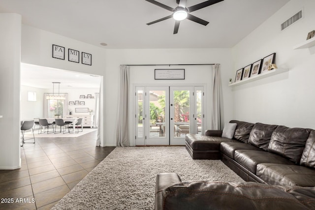 living area featuring a ceiling fan, visible vents, and dark tile patterned floors