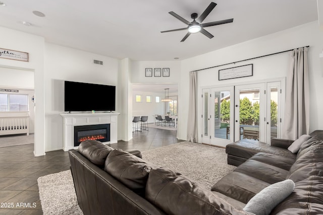living room with visible vents, a ceiling fan, dark tile patterned floors, and a healthy amount of sunlight