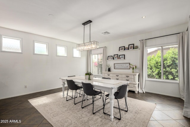 dining area featuring a notable chandelier, baseboards, visible vents, and dark tile patterned floors