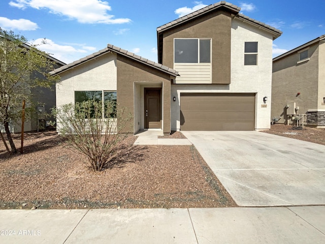 view of front facade with a garage, driveway, a tiled roof, and stucco siding