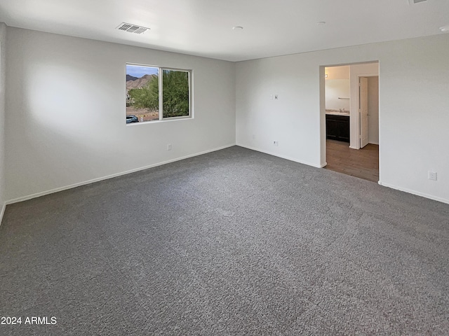 empty room with baseboards, visible vents, and dark carpet