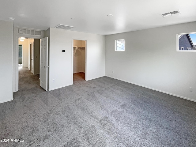 unfurnished bedroom with carpet floors, a walk in closet, and visible vents