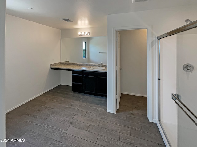 bathroom with wood-type flooring, walk in shower, and vanity