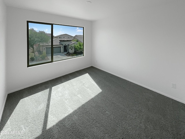 empty room with dark colored carpet and baseboards