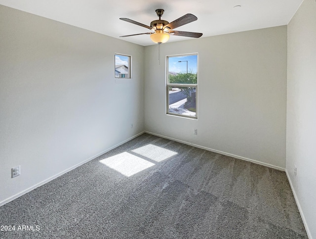 carpeted spare room featuring ceiling fan and baseboards